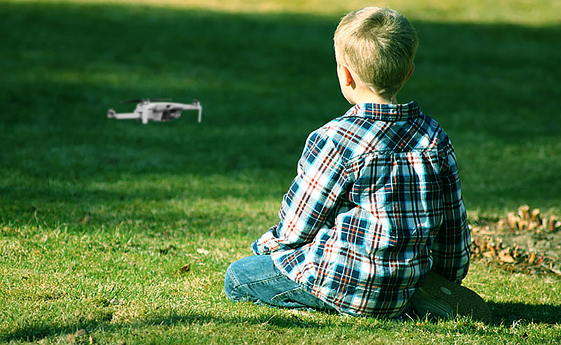 Enfant assis dans l'herbe en train de piloter un drone