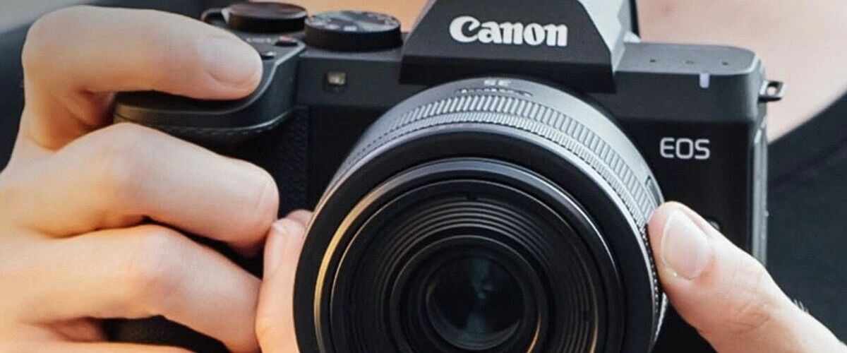 Photographe cadrant au Canon EOS R8 Mark II, les deux mains sur le boîtier